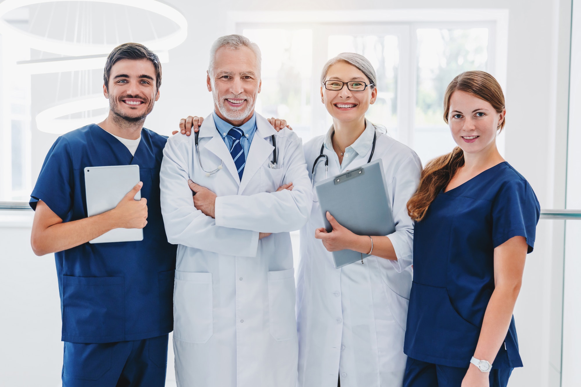 Team of medical doctors looking at camera and smiling while standing in hospital